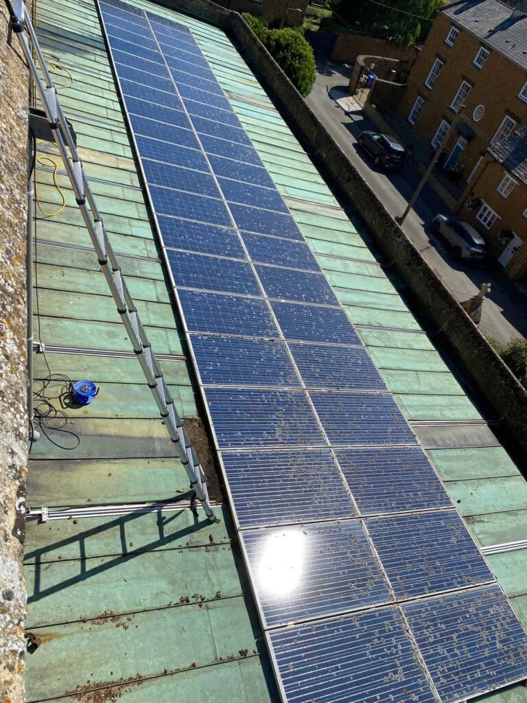 A large array of solar panels (lichen covered) on the roof of a church in Oxfordshire A large array of solar panels (lichen covered) on the roof of a church in Oxfordshire